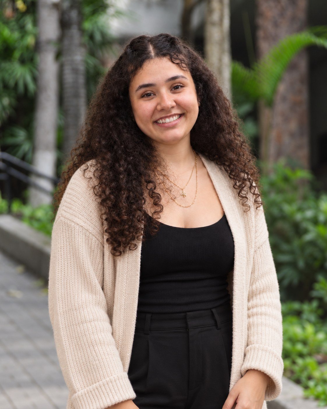 Julia Bodden, psicóloga, sorrindo ao ar livre, de cardigan bege, em um jardim